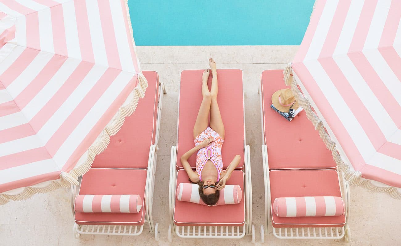 woman laying in a pink lounge chair next to the pool