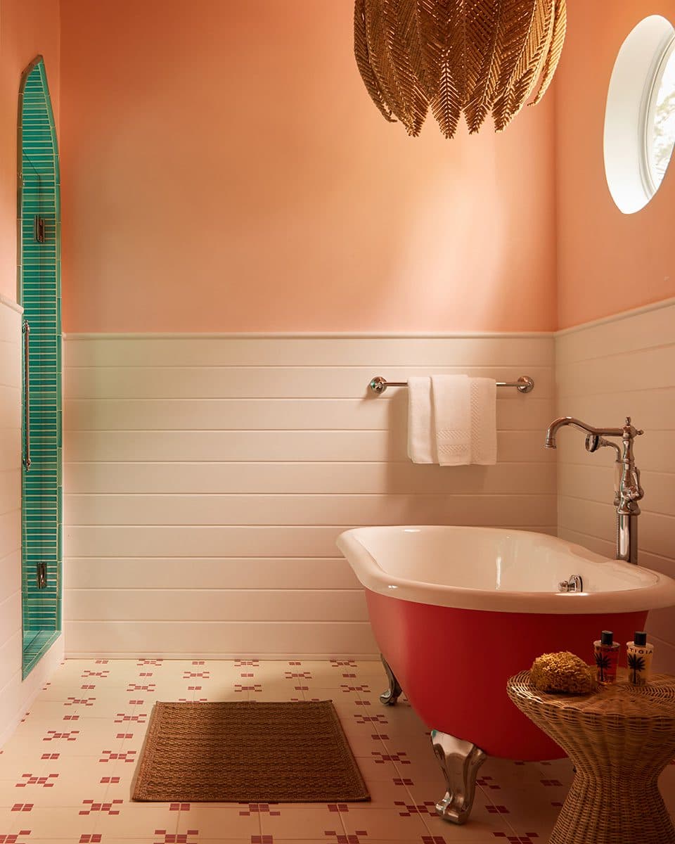 pink clawfoot bathtub and turquoise tiled shower